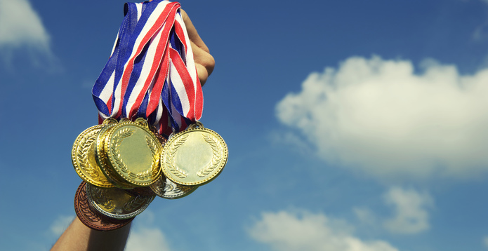 Gold Silver Bronze Medals Hand Holding Up in Blue Sky