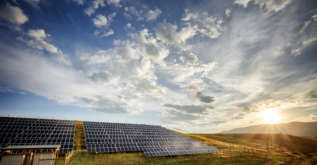 Solar Panels and Green Field Under Dramatic Sky at Sunset